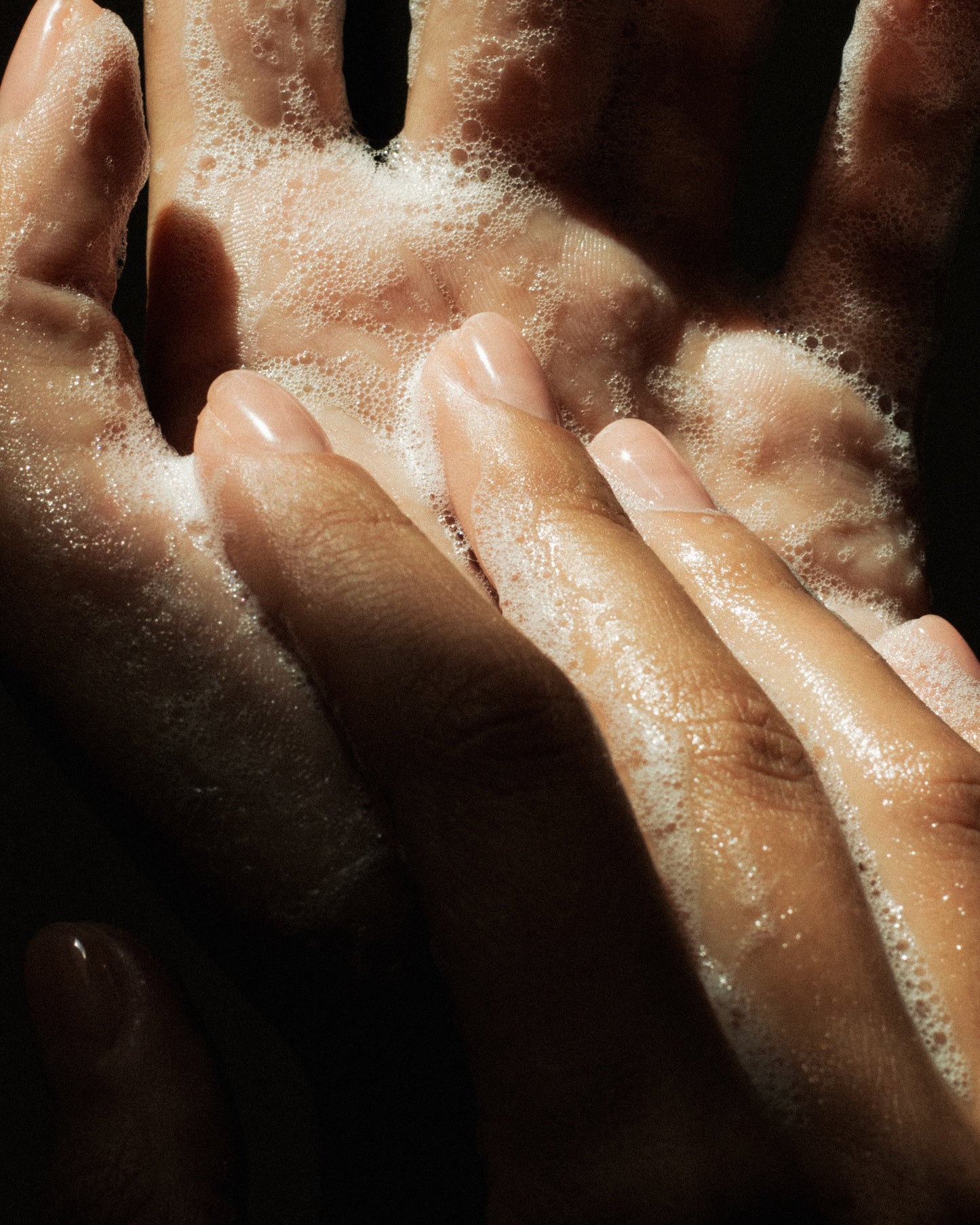 Hands working the cleanser into a lather. you can see gentle bubbles.