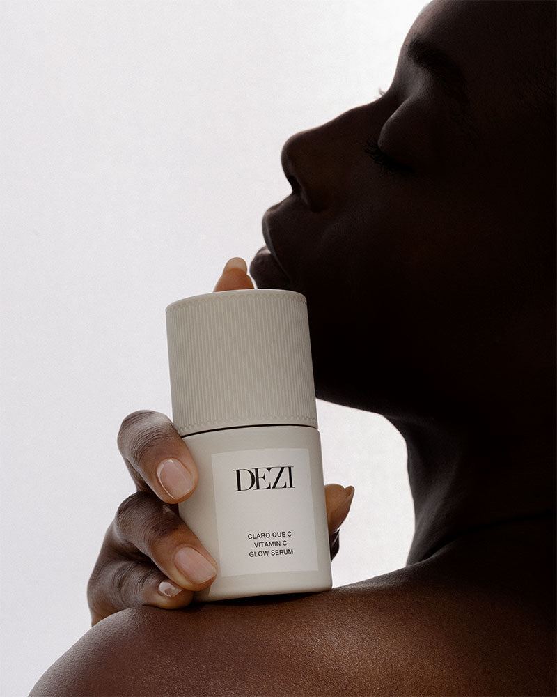 Model holding the vitamin c bottle next to her face.