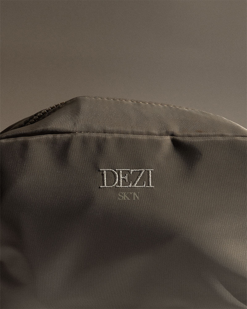 close up detail image of the cosmetic bag. it is a neutral brown color. designed by desi perkins
