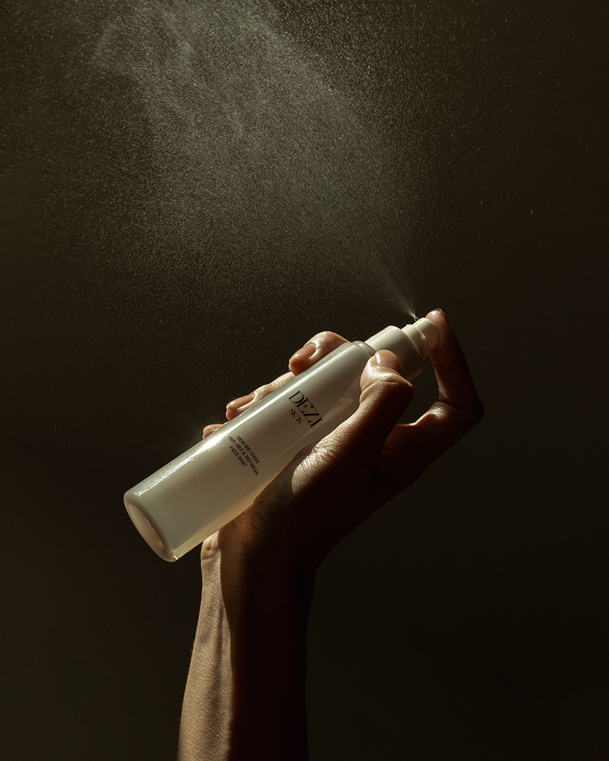 Model holding the skincare mist bottle in her hands. She is spraying the mist.