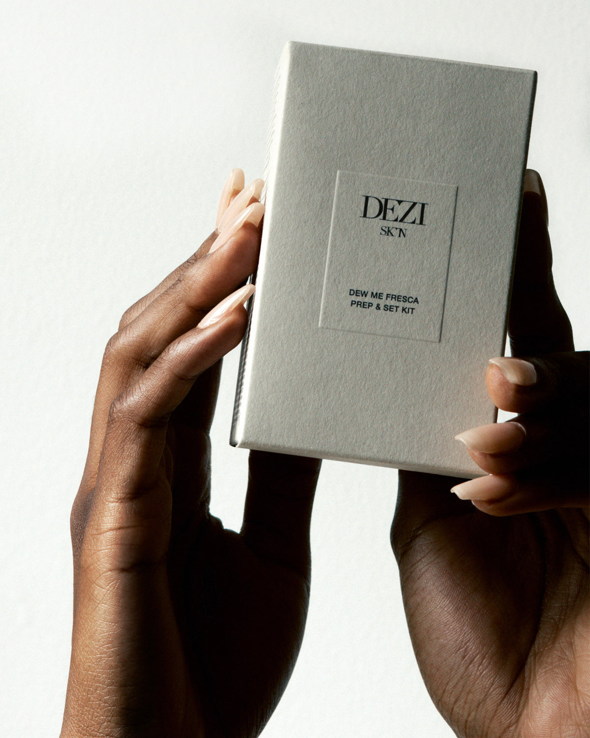 Hands holding the box with the two travel size skincare products inside. The mist and the moisturizer.