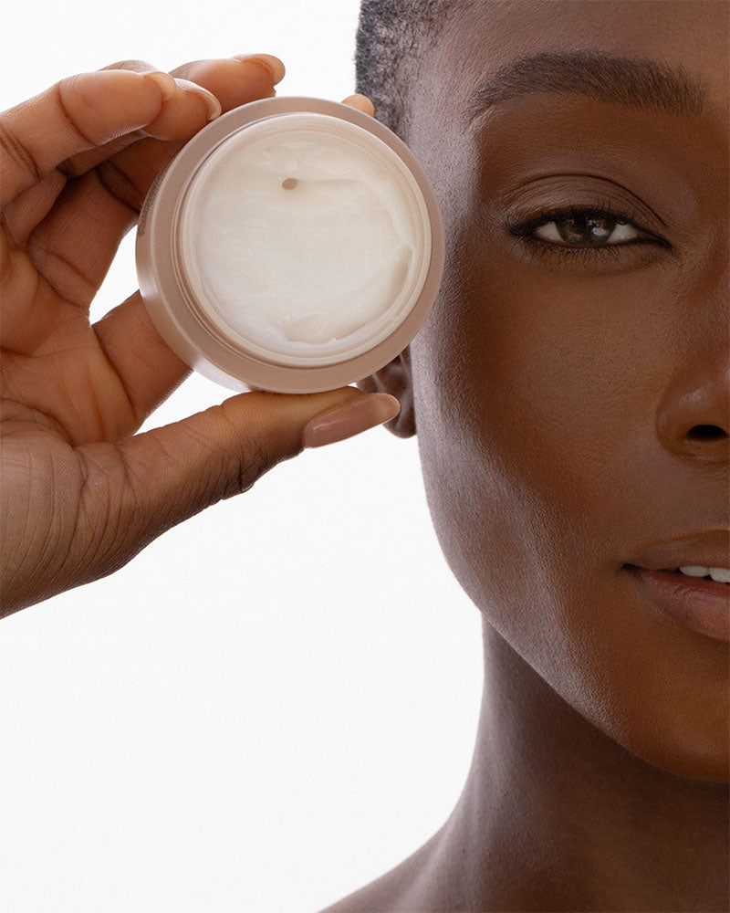 Model holding the moisturizer jar next to her face. 