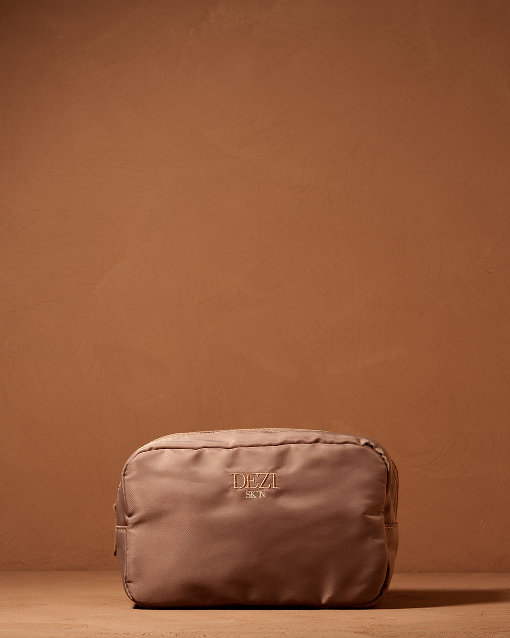 This is a picture of a small cosmetic / toiletry bag. It is a beautiful neutral brown color. Made of nylon with a zipper on the top. 